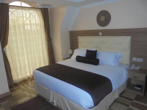 a bedroom with a large bed and a clock on the wall at Villa Leone Boutique Hotel in Nairobi
