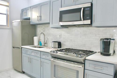 a kitchen with a stove and a microwave at Cozy modern Bellerose in Bellerose
