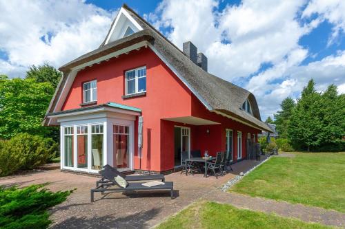 una casa rossa con tavolo e sedie nel cortile di Reethaus StrandZeit in Lobbe - Haushälfte 2 a Lobbe
