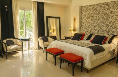 サン・ミゲル・デル・モンテにあるPosada Suiza by Prima Collectionの赤いクッションと椅子が置かれた大きなベッドのある寝室