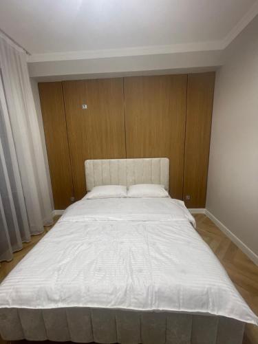 1 cama blanca grande en una habitación con paredes de madera. en ЖК Керуен Сарай, en Türkistan