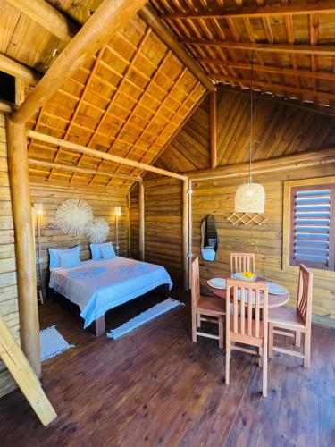 a bedroom with a bed and a table and chairs at Chalet Paraiso Canoa 3 na praia - Canoa Quebrada in Aracati