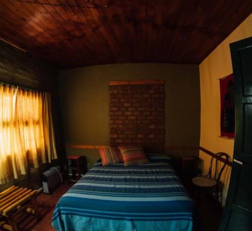 a bedroom with a bed and a brick wall at Hostel Barreal in Barreal