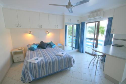 Coral Point Lodge في Shute Harbour: غرفة نوم بسرير ومطبخ مع طاولة