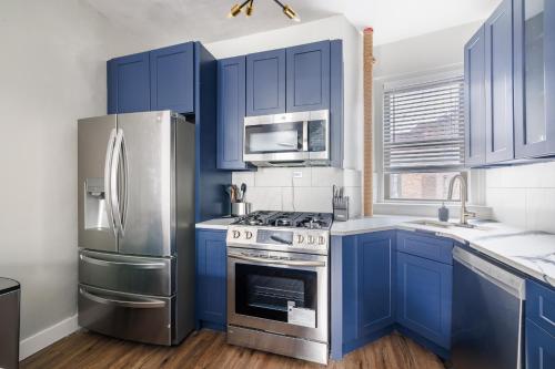 a kitchen with blue cabinets and stainless steel appliances at Ultimate Urban living at Centrally Located Apartments in New York