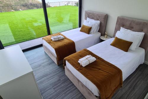 two beds in a room with a large window at Luna Villa in Campanário
