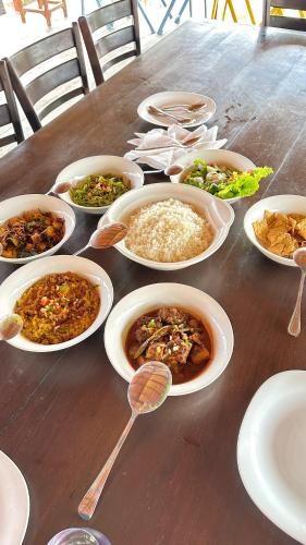 a wooden table with bowls of food and plates of food at Sunset Serenity Villa in Ahangama