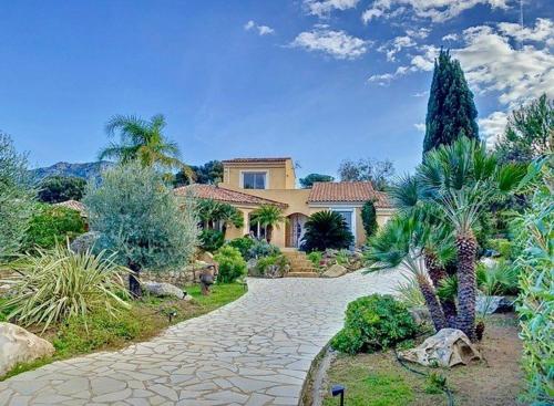 a large house with a driveway in a garden at Villa avec piscine à quelques minutes de la mer in Lumio