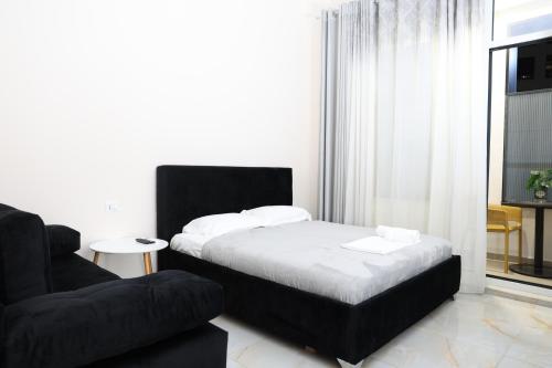 a bedroom with a bed and a black chair at Luxe Living Studio in Tirana