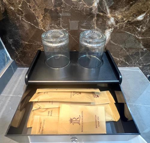 Dại MõRoyal Louis Hotel的托盘上放着两个玻璃杯和几个盒子。