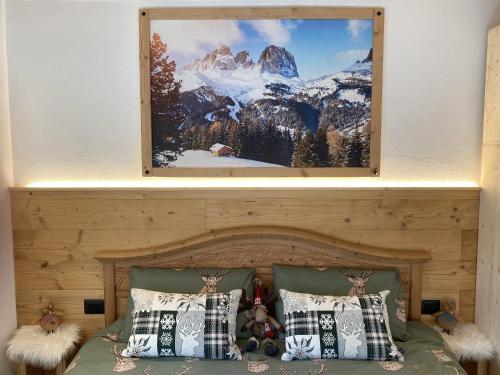 a bedroom with a bed with a picture on the wall at My Sweet Home in the Dolomites - appartamento "Ai Vòlti" in Cavalese