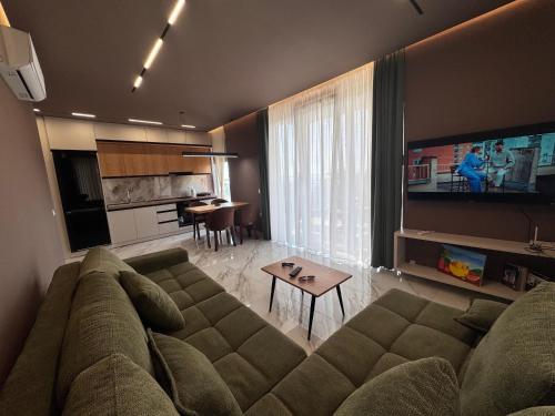 レジャにあるSunset Luxury Apartment Shengjinのリビングルーム(大きなソファ付)、キッチンが備わります。