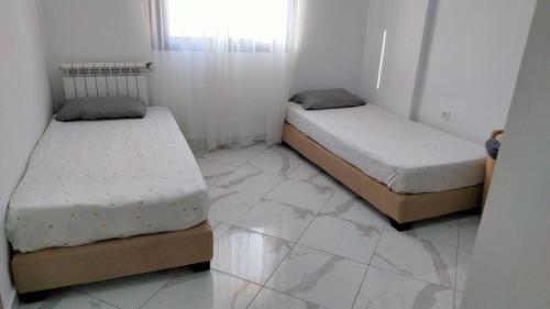 two beds in a room with a tiled floor at 2 chambres à Belgaid in Bir el Djir