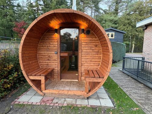 eine Holzsauna mit Holztür im Hof in der Unterkunft Sfeervolle villa met sauna aan de rand van het bos in Putten