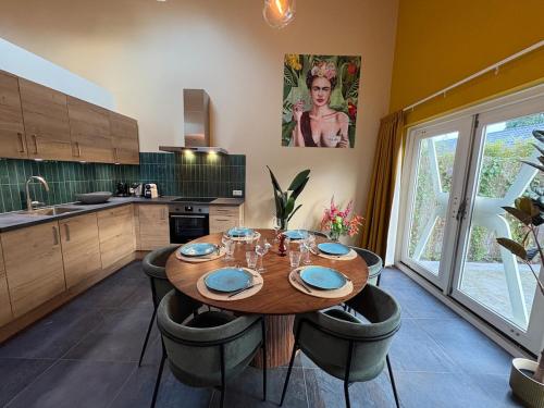 eine Küche mit einem Holztisch und einigen Stühlen in der Unterkunft Sfeervolle villa met sauna aan de rand van het bos in Putten