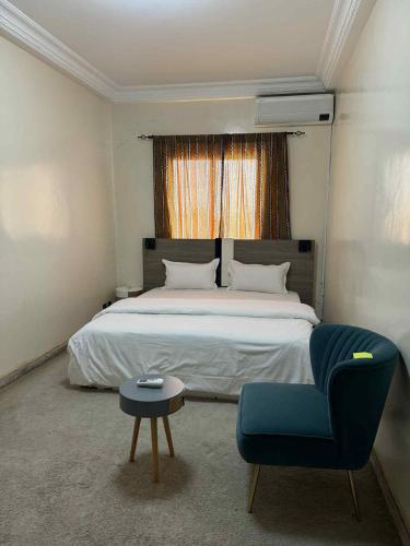 a bedroom with a bed and a chair and a table at MAISON Khadija Abibatou in Dakar