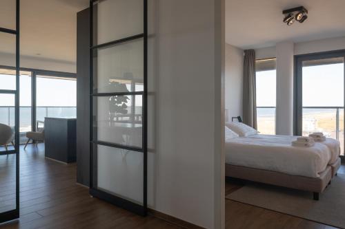 Schlafzimmer mit einem Bett und Glasschiebetüren in der Unterkunft Droomsuites Egmond aan Zee 4 personen by Droomvilla in Egmond aan Zee