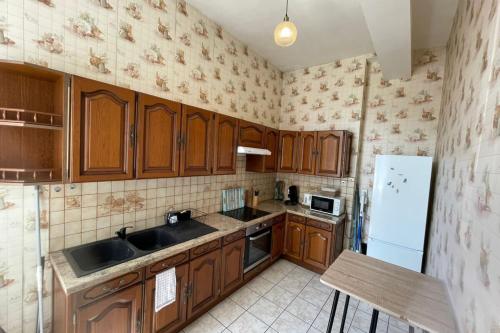 a kitchen with wooden cabinets and a sink and a refrigerator at Les Pieds dans le Bassin in Le Havre