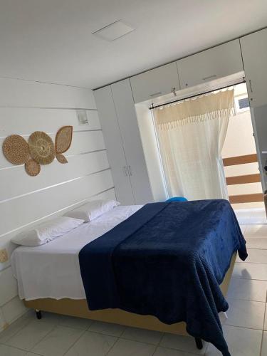 a bedroom with a bed with a blue blanket and a window at Chalé em Praia Bela Paraíba in Pitimbu