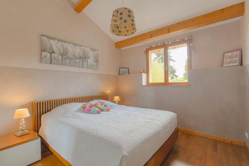 a bedroom with a bed with white sheets and a window at Les Aubépines en Beaujolais in Salles-Arbuissonnas
