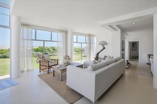 Beachfront, Sea Views, WiFi, Fireplace, 1-Min Walk في Cape Town: غرفة معيشة بيضاء مع أريكة وطاولة