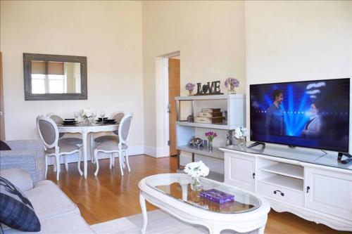 a living room with a large television and a table at The Palm Suite in Southport