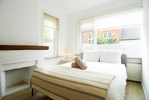 a white bedroom with a bed and a fireplace at spacious new appartment in Lisse