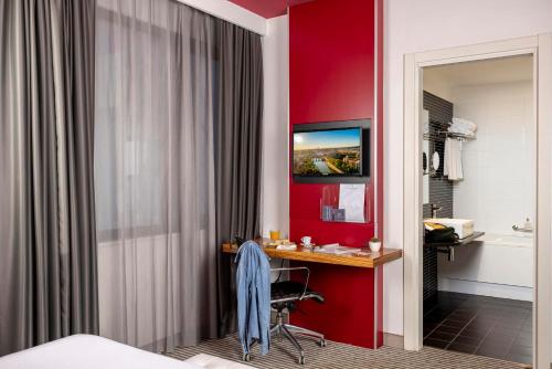 een hotelkamer met een bureau in een rode muur bij The Caesar Roma in Rome