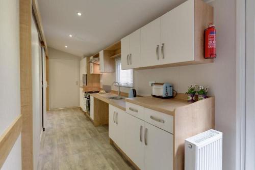 a kitchen with white cabinets and a counter top at Mersea Island by Away Resorts in Colchester