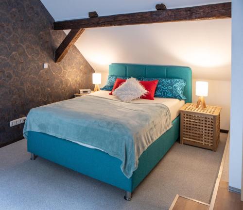 un dormitorio con una cama azul con almohadas rojas en Ferienhaus im Pochwerksgrund in Suhl Goldlauter im Thüringer Wald, en Suhl