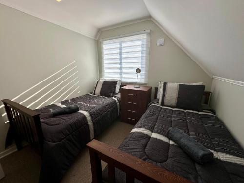 a attic bedroom with two beds and a window at Latitud Guesthouse in Puerto Montt