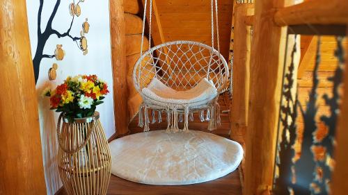a chair sitting on a porch with a vase of flowers at Căsuța Melimi cu piscină încălzită, ciubăr și saună in Râșca