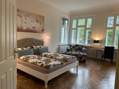 a bedroom with a bed and a chair and windows at Villa Deichvoigt in Cuxhaven