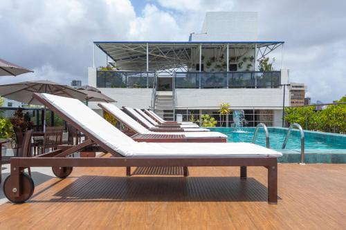 a row of lounge chairs next to a swimming pool at Atlântico Praia Hotel in João Pessoa