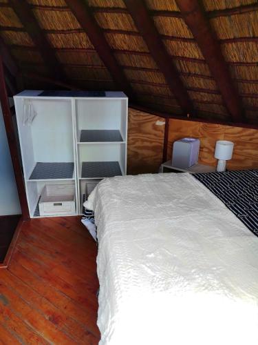 a bedroom with a white bed and a wooden floor at Slakkepas Sela in Dwarskersbos