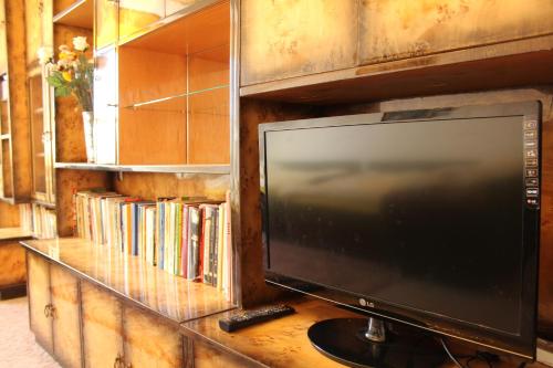 a television sitting on a table with a book shelf at Arkady in Słupsk