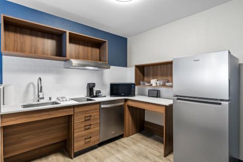 a kitchen with a white refrigerator and wooden cabinets at Everhome Suites Ontario in Ontario