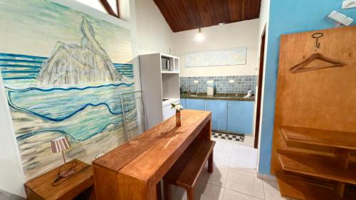 une cuisine avec une table en bois et un tableau mural. dans l'établissement Flat Siriguela, à Fernando de Noronha