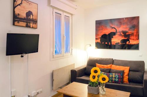 a living room with a couch and a tv at Gran Via Alaia Seasonal Living in Madrid