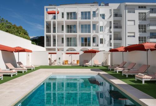 a swimming pool with chairs and umbrellas in front of a building at Vila Catarina Luxury Apartments in Porto