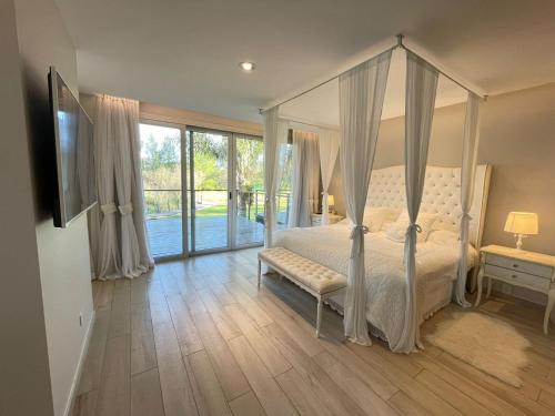 a bedroom with a canopy bed and a sliding glass door at La Posada Multiespacios in Dique Luján