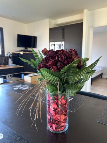 un jarrón lleno de rosas rojas en una mesa en Villa Egret - Wifi - Jardin, en Dinard