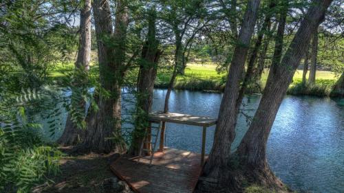 a chair sitting on a boardwalk next to a river at Humming Bird Haven in Utopia