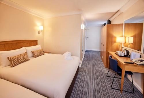 a hotel room with a bed and a desk at Thistle London Heathrow Terminal 5 in Hillingdon