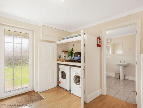 eine Waschküche mit Waschmaschine und Trockner in der Unterkunft Hen Cottage in Little Torrington