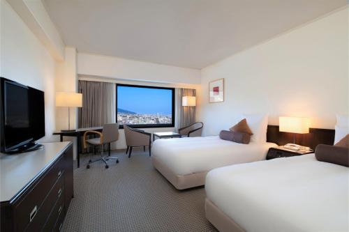 a hotel room with two beds and a flat screen tv at ANA Crowne Plaza Kobe by IHG in Kobe