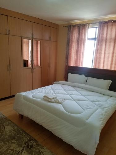 a large white bed in a bedroom with a window at Almasi airport view apartment in Syokimau