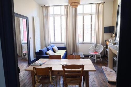 a living room with a table and a blue couch at Agréable maison avec jardin dans le centre historique de Bourdeilles in Bourdeilles