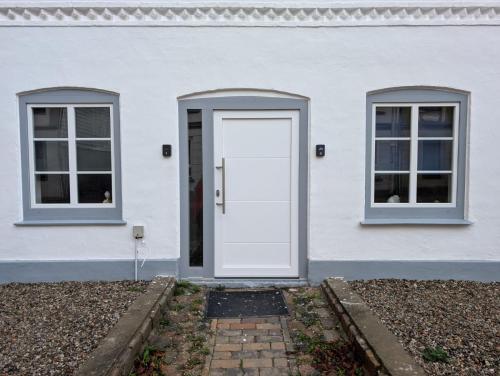 a white house with a white door and two windows at Stadtnah an der Förde 5502 in Flensburg