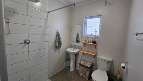 a white bathroom with a toilet and a sink at 32 Main Road in Struisbaai